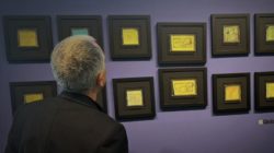 A person looks at a selection of framed drawings from the #NoteOlvides campaign at an ISGlobal exhibition.