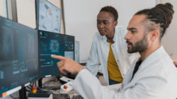 Dues persones amb bata blanca davant l'ordinador.