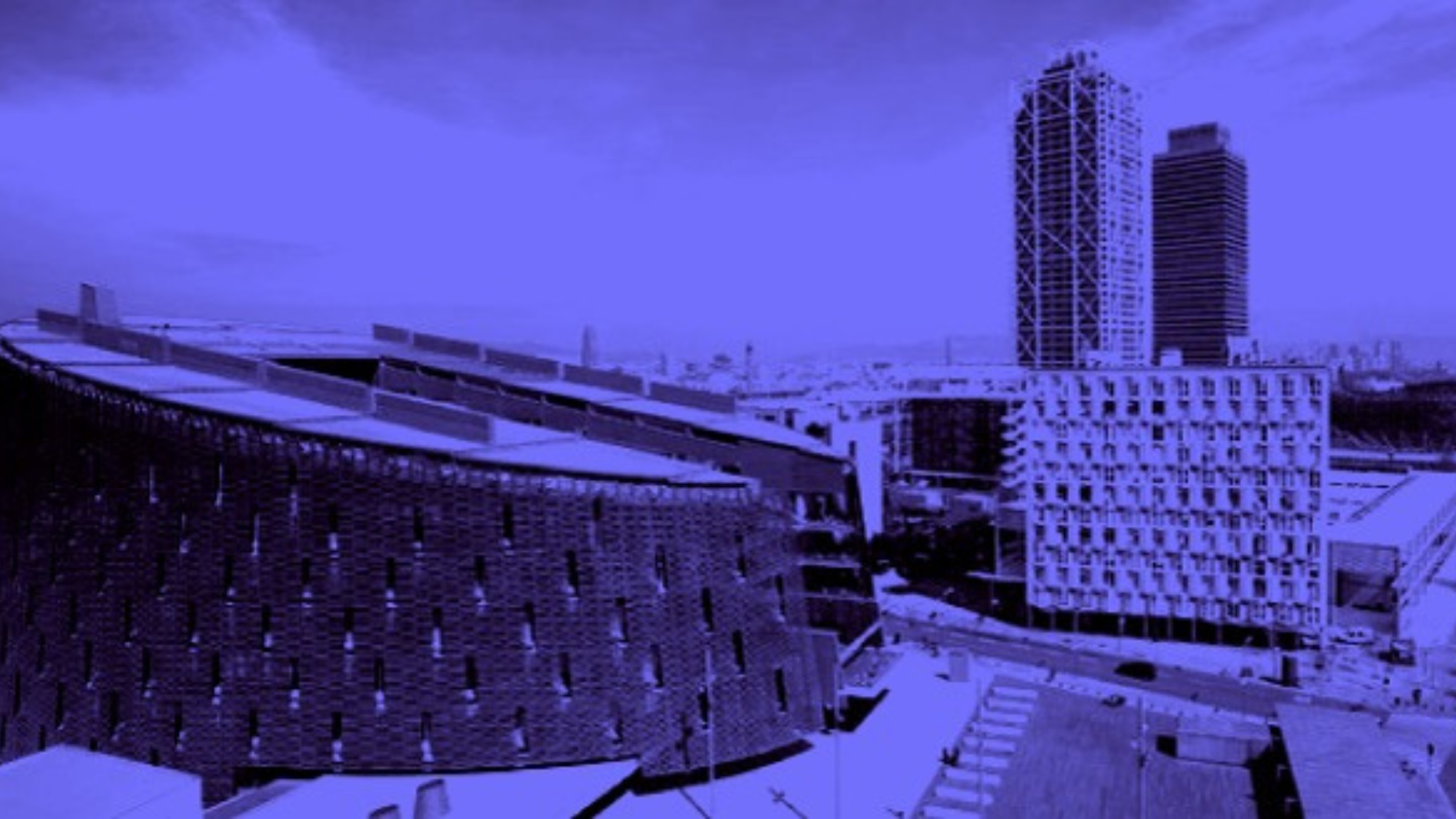 Vista exterior con filtro azul del edificio del PRBB y el frente marítimo de Barcelona.